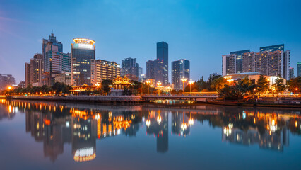 Obraz premium Night view of modern city skyline with river reflection
