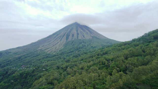 Cinematic aerial trucking shot from right to left showcasing the iconic triangular peak of Mount Inerie and its lush volcanic slopes in Flores.