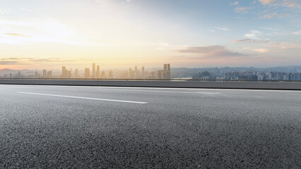 Asphalt Road with City Skyline at Sunset