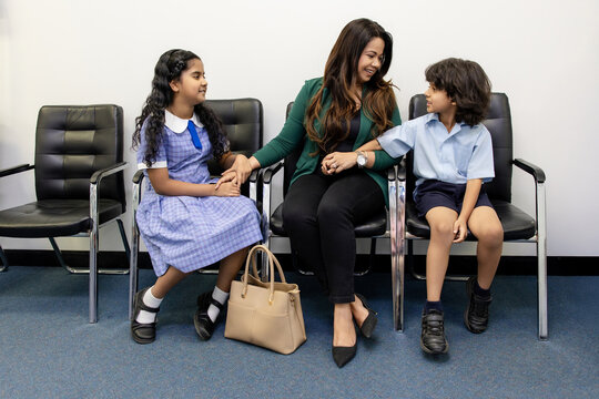 Mother with her two kids seated on waiting area of doctors clinic
