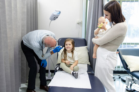Doctor checking young girls ear with otoscope