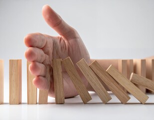 Stopping the Domino Effect - A Hand Preventing Wooden Blocks from Falling.