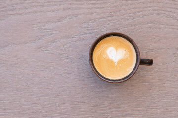 small coffee in a brown earthenware cup with loveheart