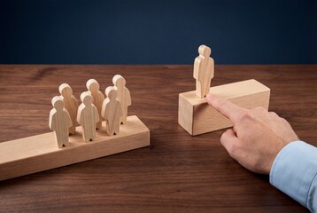 Male hand choosing wooden figure on high block representing leadership selection and hierarchy