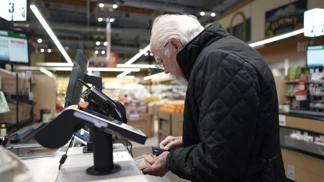 An elderly man faces problems at the checkout in a grocery store as he tries to pay for his items and finish his shopping.