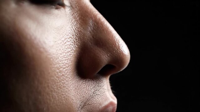 Close up of a human nose and face with textured skin against black backdrop