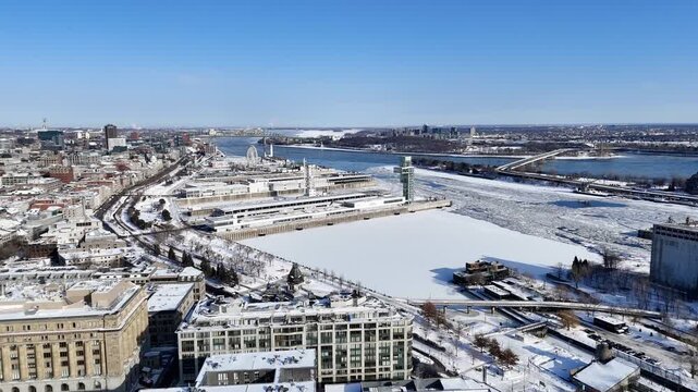 Aerial winter view of Montreal Old Port and frozen St Lawrence River with city skyline and harbor infrastructure. g.