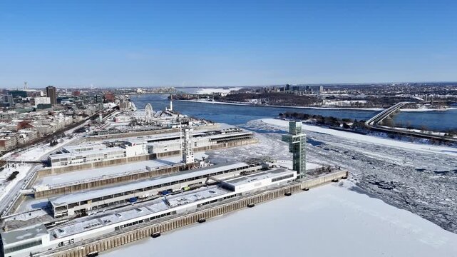 Aerial winter view of Montreal Old Port and frozen St Lawrence River with city skyline and harbor infrastructure. g.