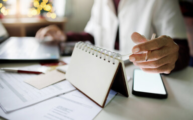 close up shot, asian man checking schedule work in calendar working on desk with laptop and...