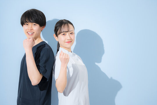 水色背景で爽やかな看護師イメージの若い男女　新卒採用や転職の求人などに　ガッツポーズや頑張るぞ～のポーズ　カメラ目線