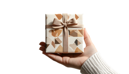 A hand holding a stylish square gift box with geometric patterns and a gold ribbon.