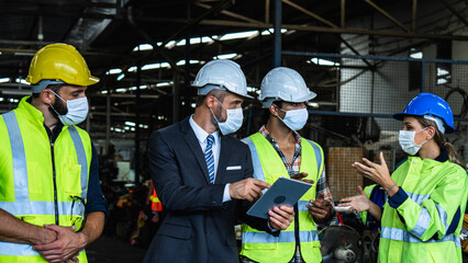 Factory Manager and Engineers Wearing Masks Reviewing Data on Tablet