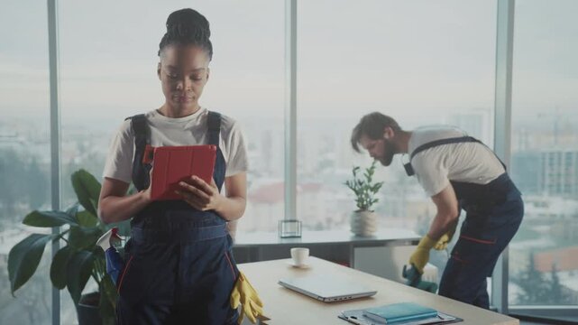 Female manager supervising, African American woman supervising cleaning staff with digital checklist in urban setting