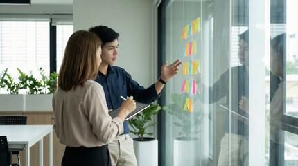 Asian Business Team Analyzing Project Strategy with Sticky Notes and Tablet
