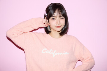 ピンク背景でキュートなポーズをする若い女性のポートレート