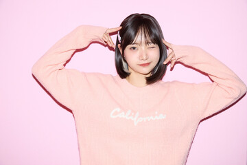 ピンク背景でキュートなポーズをする若い女性のポートレート
