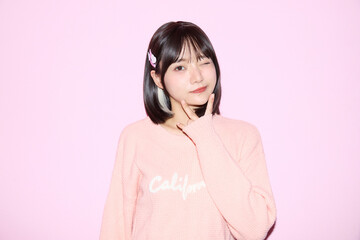 ピンク背景でキュートなポーズをする若い女性のポートレート
