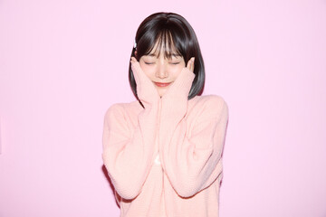 ピンク背景でキュートなポーズをする若い女性のポートレート