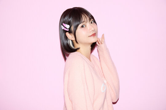 ピンク背景でキュートなポーズをする若い女性のポートレート