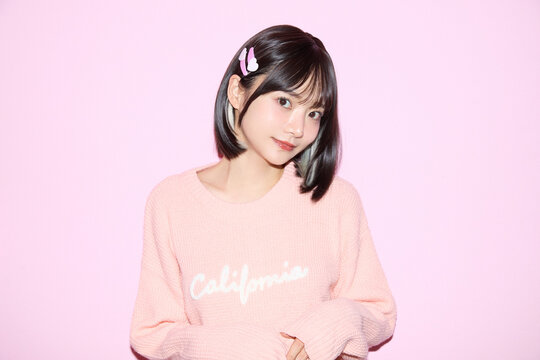 ピンク背景でキュートなポーズをする若い女性のポートレート