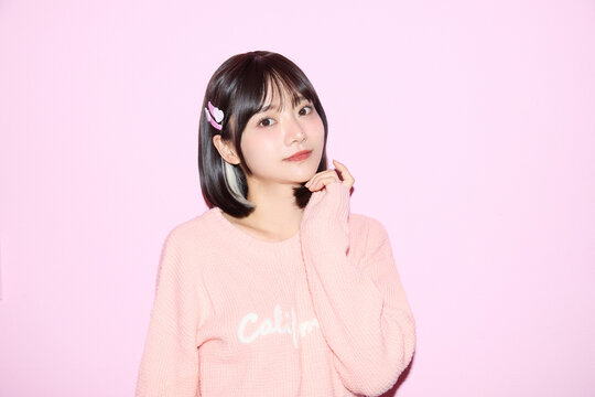 ピンク背景でキュートなポーズをする若い女性のポートレート
