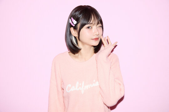 ピンク背景でキュートなポーズをする若い女性のポートレート
