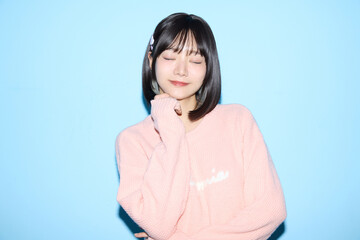 ブルー背景でキュートなポーズをする若い女性のポートレート