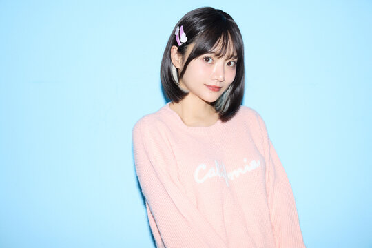 ブルー背景でキュートなポーズをする若い女性のポートレート