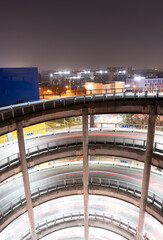 Night view of a modern urban multi-story spiral parking garage.