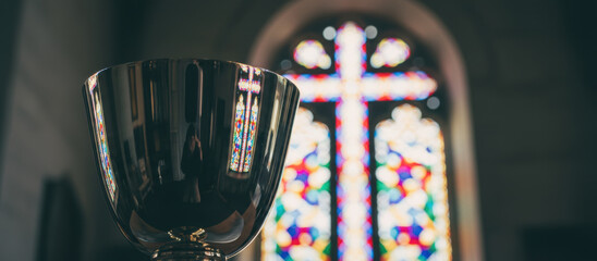 Silver chalice cross reflection church altar stained glass window sacred religious ritual worship reverent mood