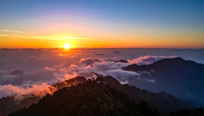 Obraz premium Aerial view of a mountain range at sunrise, clouds below