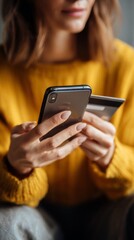 Young woman shopping online with smartphone and credit card at home, vertical photo