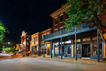 Fototapeta premium Illuminated shops and cafes on historic Main Street dating back to the 18th century in the old town historic district of St. Charles, Missouri, at night.