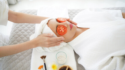 Masseuse masking face with tomato and spa face woman treatment and massage aroma therapy relax enjoying and healthy and beauty. Spa Thai therapy treatment aromatherapy for body and face