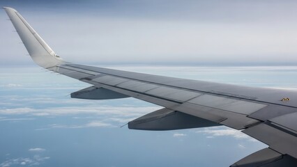 Obraz premium View of an airplane wing soaring above the vast ocean and scattered clouds on a cloudy day.