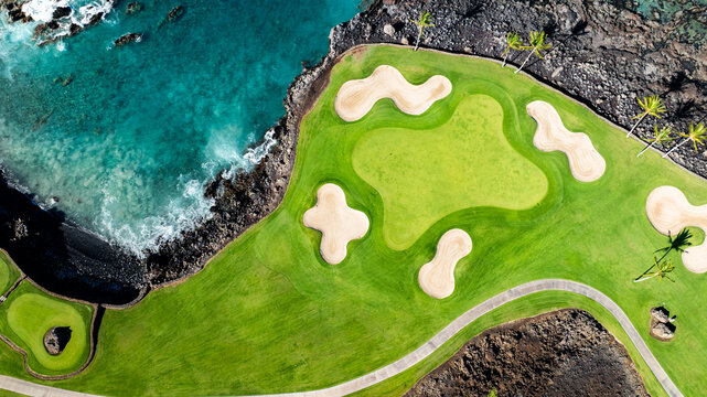 Aerial bird's eye view of Big Island, Hawaii landscapes with a golf course green  amidst the natural volcanic terrain and greenery coastline near Waikoloa Beach resort