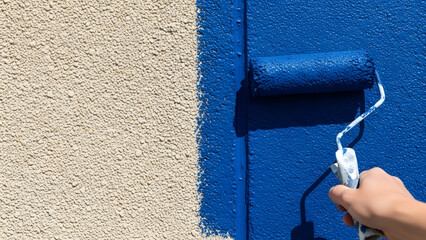 Hand painting a textured wall with a blue paint roller renovation and home improvement concept close-up detail shot
