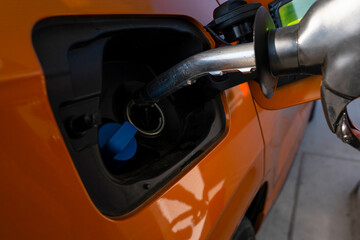 Filling up gas at a station with a fuel pump during the day in a bright location