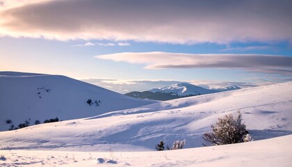 Panoramic winter mountain view with snow-covered hills under a cloudy sky