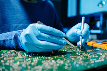 Close up of technician soldering and repairing circuit board in a modern laboratory, electronics repair, engineering, technology, maintenance and quality control concept.