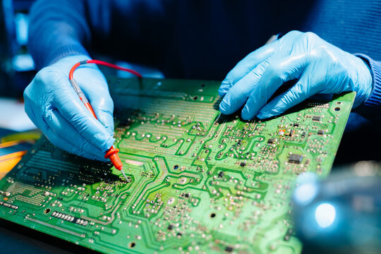 Close up of technician soldering and repairing circuit board in a modern laboratory, electronics repair, engineering, technology, maintenance and quality control concept. - Powered by Adobe