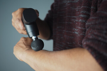 Man uses massage device on arm for relief and recovery