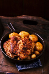Fried chicken breast with potatoes. Rustic wooden background. Soft focus.
