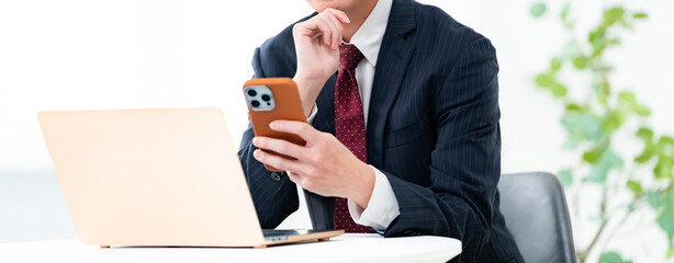 パソコンと携帯を見る男性