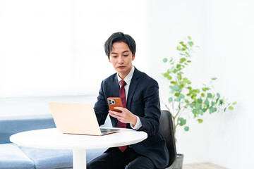 パソコンと携帯を見る男性