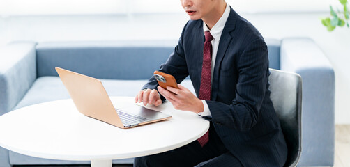 パソコンと携帯を見る男性