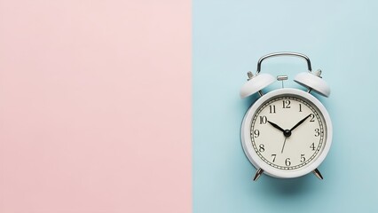 A white alarm clock sits on a pastel background split between pink and light blue, symbolizing time and punctuality.