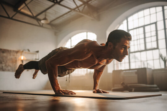 Athletic European Man Executing Dynamic Strength Yoga Pose on Mat