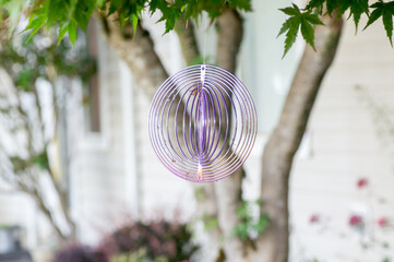 A spinning decorative ornament hanging from a tree in the backyard.