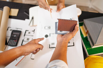 
Two people are working on a house plan design. They are using various tools, working with the...